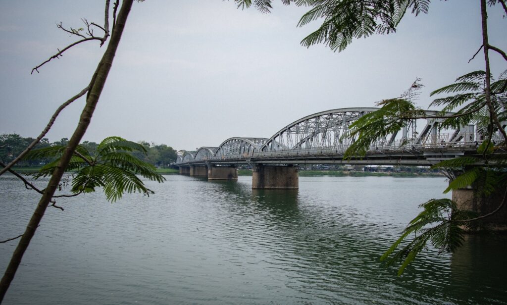a bridge over a body of water with trees in the foreground