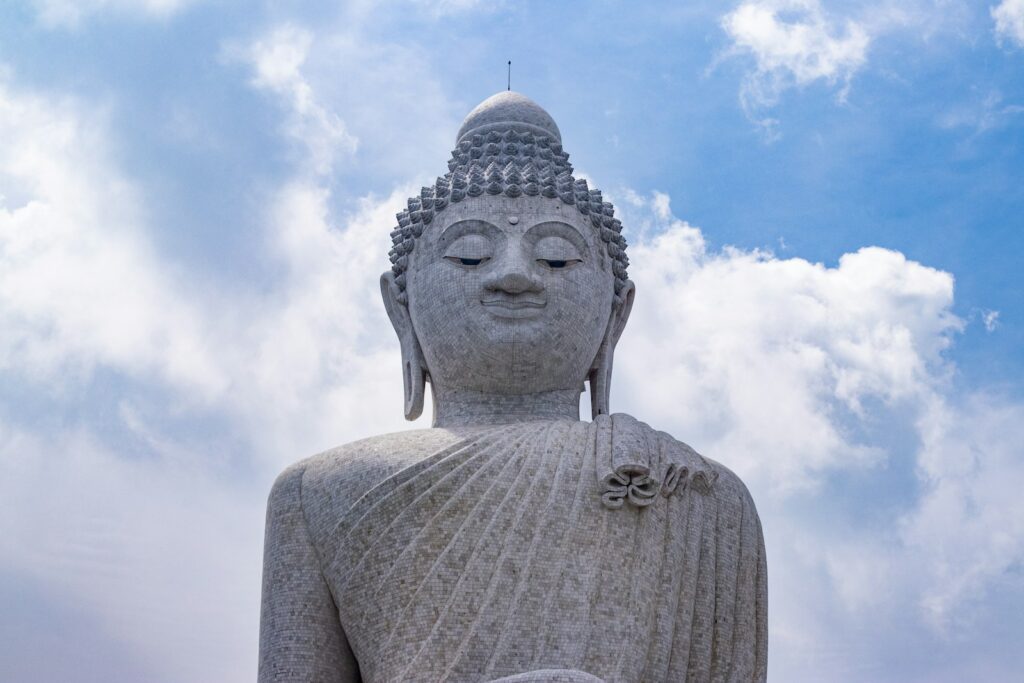 a large buddha statue sitting under a cloudy blue sky