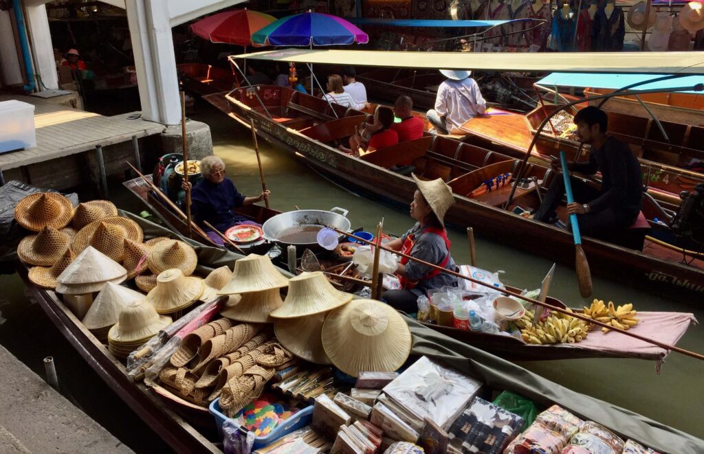 Vendor boats selling hats, sandals and bananas at Damnoen Saduak Floating Market.